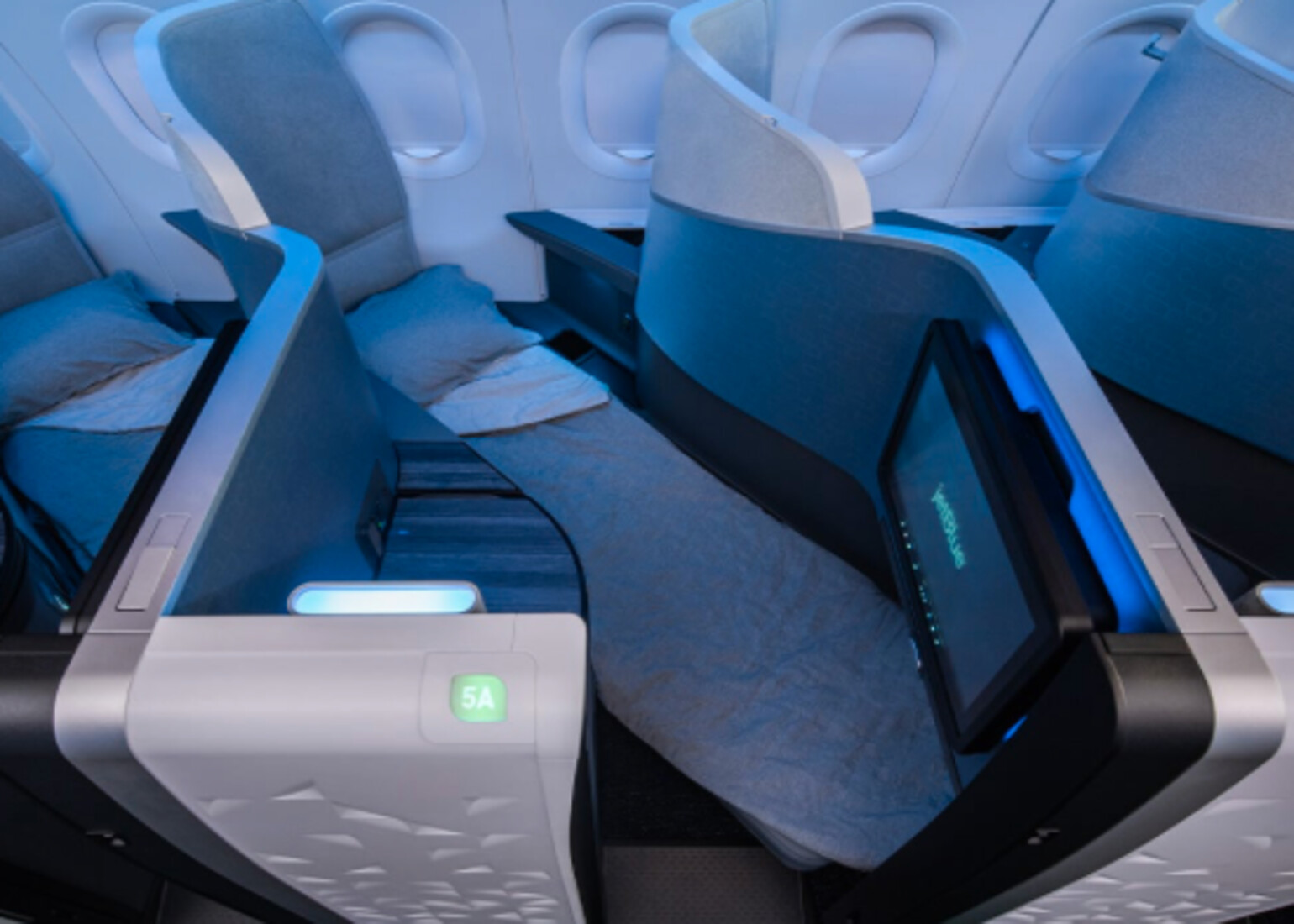 JetBlue Mint Suite on the A321LR — a lie-flat business class seat made up for sleep, with the seatback screen, sliding privacy divider, and the 1-1 cabin layout