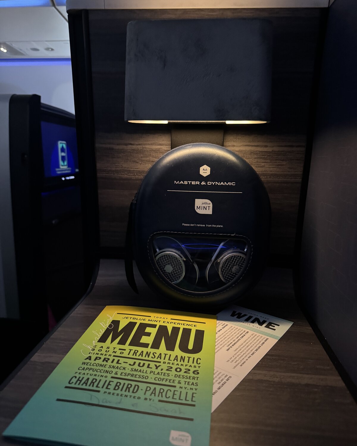 Master and Dynamic headphones and the signed JetBlue Mint menu waiting at the suite, lit by the suite's reading lamp