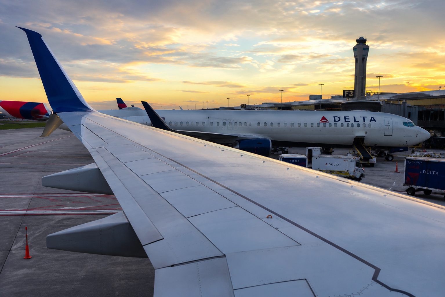 Delta SkyMiles Amex cards 2026 refresh — a Delta Boeing 737 at the gate at sunset, viewed over the wing