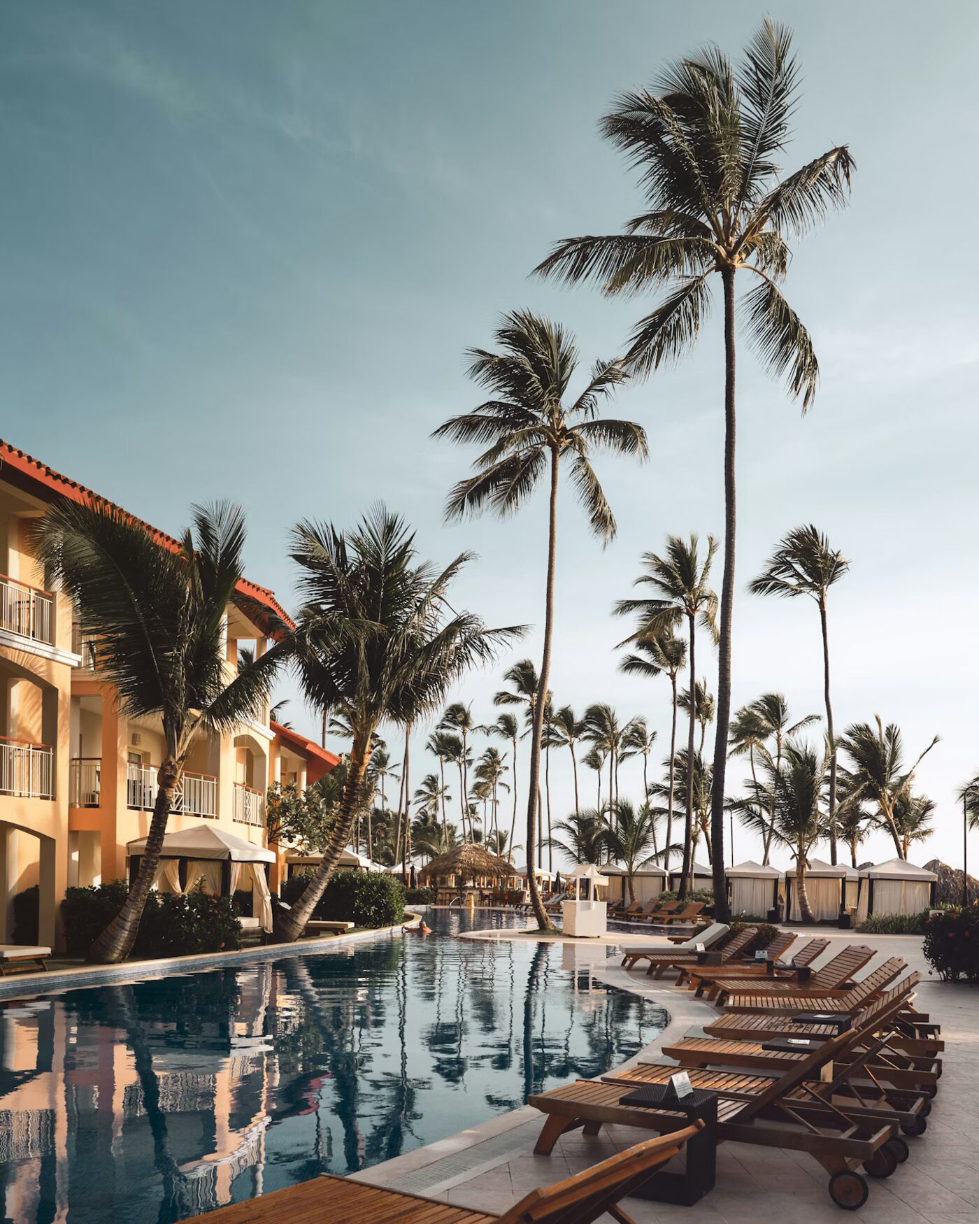 Tropical resort pool with palm trees at golden hour — the kind of stay points unlock at a fraction of cash price